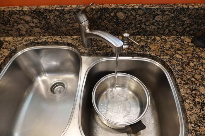 The Grohe Eurosmart Single-Handle Dual Spray Kitchen Faucet with water flowing into a pan in a kitchen sink.