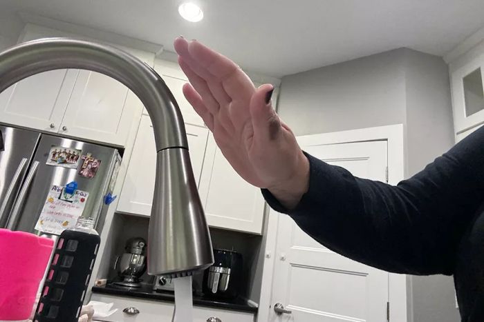 A person operating the touchless sensors on the Moen Arbor One-Handle High Arc Smart Kitchen Faucet.