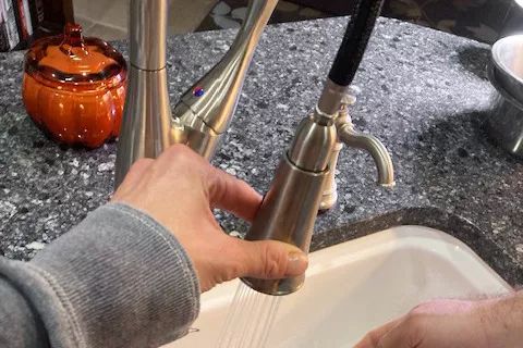 A user operating the sprayer hose of the BioBidet Flow Pull-Down Sprayer Faucet With Motion Sensor.