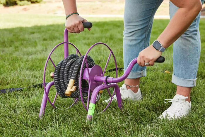 A person operating the handle on the Yard Butler Hose Reel