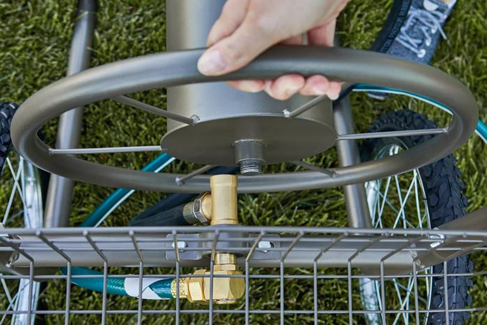 Close-up of a hand winding the hose into the GroundWork Hose Reel Cart using the wheel