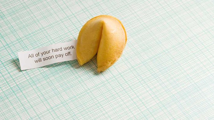 A fortune cookie and its fortune placed on a green striped background.