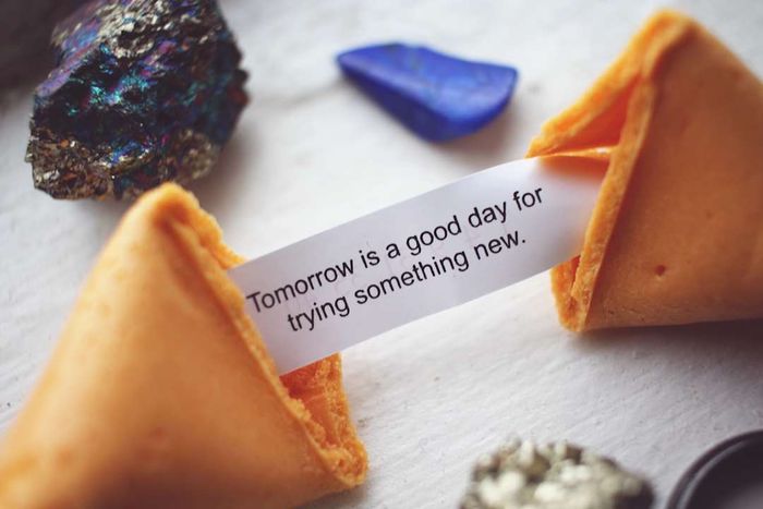 An open fortune cookie and its fortune placed on a table.