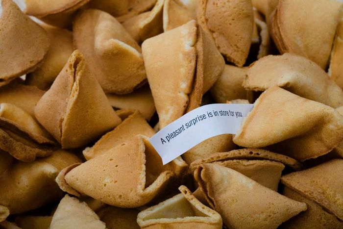 A stack of fortune cookies, with one opened to show its hidden fortune.