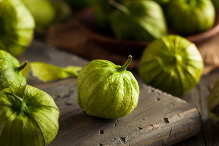 Green tomatillos resting on a wooden counter