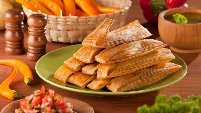 A plate of tamales, beautifully presented with garnishes.