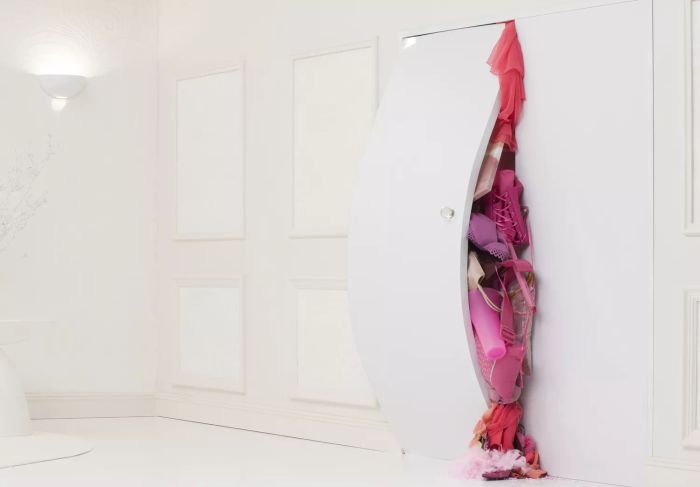 A bulging white closet door packed with pink clothes