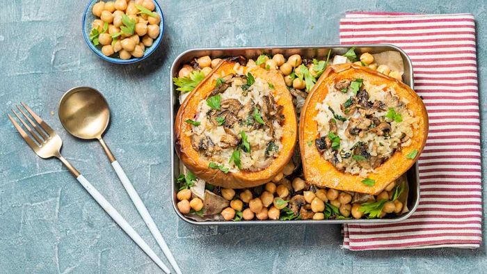 Squash filled with rice, mushrooms, and chickpeas on a baking sheet.
