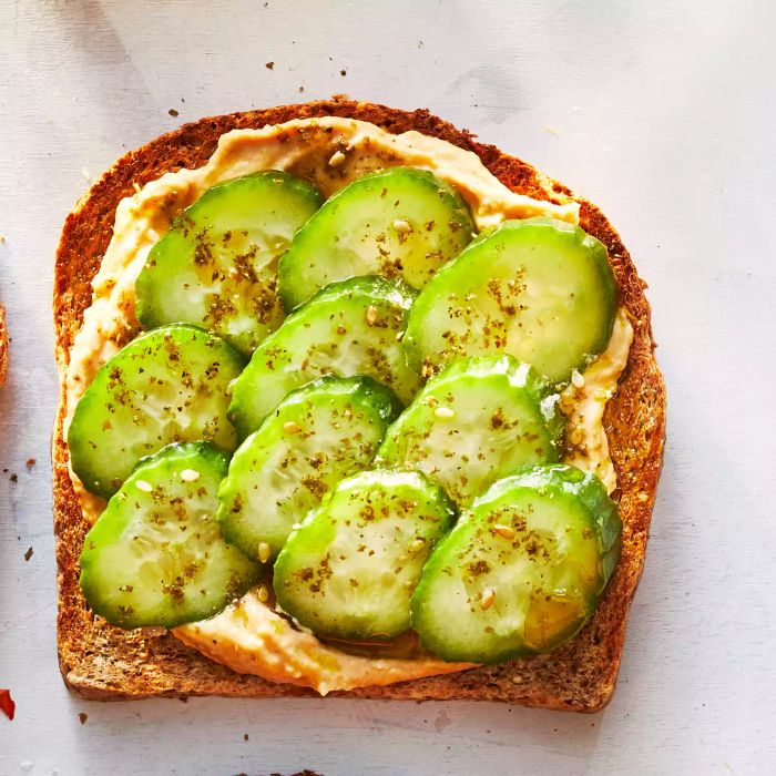 This recipe for hummus and cucumber toast combines Persian cucumbers with creamy hummus and a dash of za'atar spice mix for a delightful, refreshing bite.