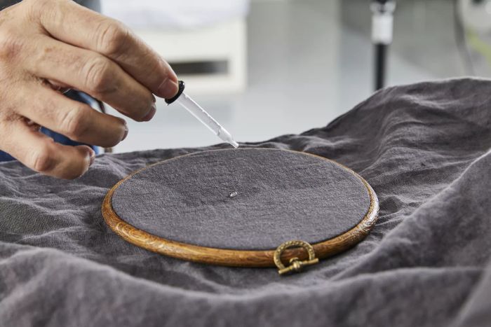 A hand using a dropper to apply liquid onto the Quince European Linen Sheet Set
