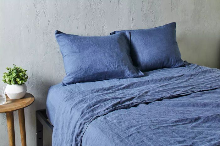 A pair of pillows with the Citizenry Stonewashed Linen Sheet and pillowcases on a bed