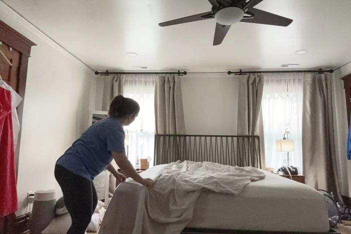A person laying out the Rough Linen Smooth Linen Sheet Set