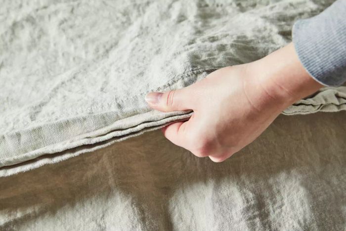 A person touching the fabric of the Parachute Linen Sheet