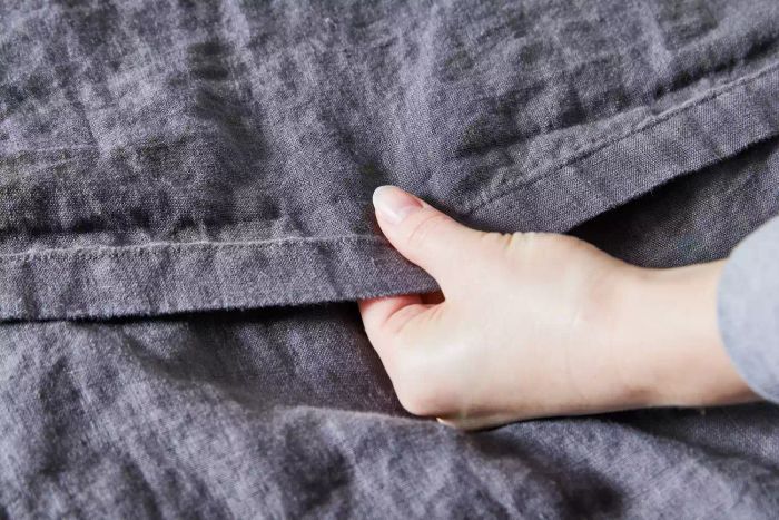 Close-up of a hand feeling the texture of the Quince European Linen Sheet Set