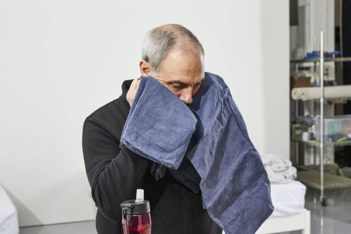 A man holding the Citizenry Stonewashed Linen sheet and pillow against his face