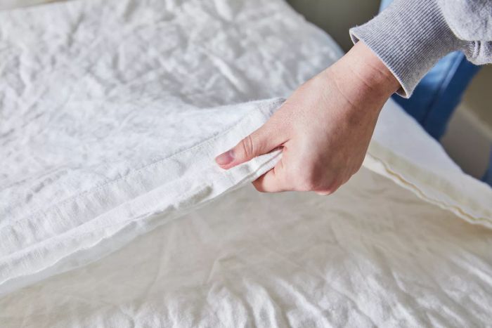 A hand touching the texture of the Saatva Linen Sheet Set