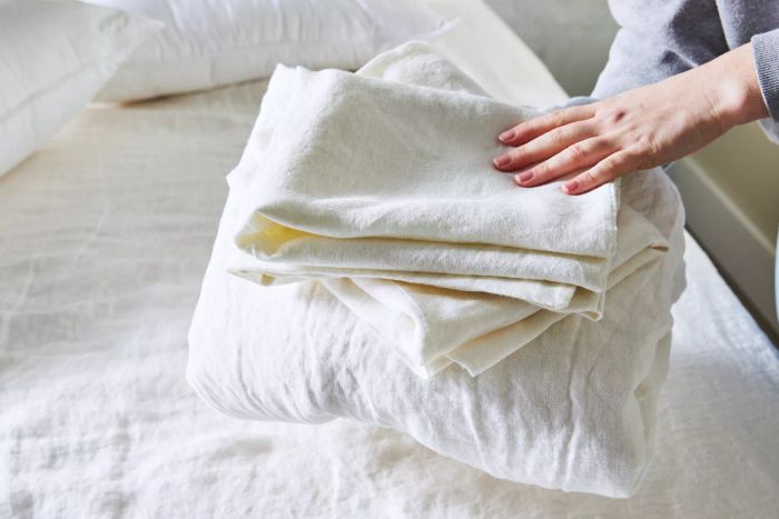 Hands holding a small stack of Saatva Linen Sheet Set sheets