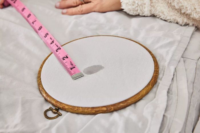 A measuring tape placed on the Quince Linen Bamboo Sheet Set next to a stain