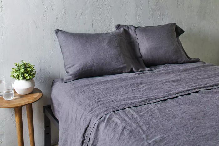 Quince European Linen Sheet Set arranged on a bed beside a wooden nightstand