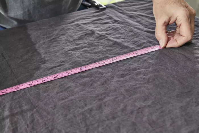 A person measuring the Quince European Linen Sheet with a tape during testing