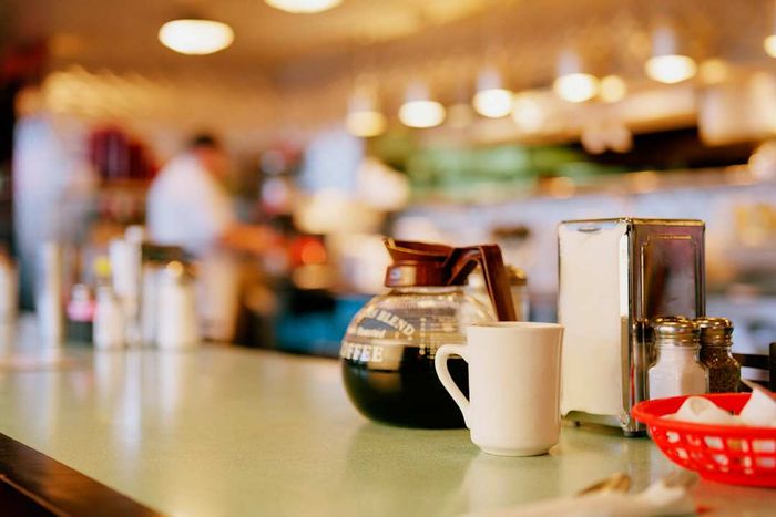 A diner countertop featuring a coffee pot, cup, and napkin dispenser