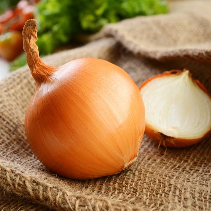 A yellow onion resting on a burlap backdrop.