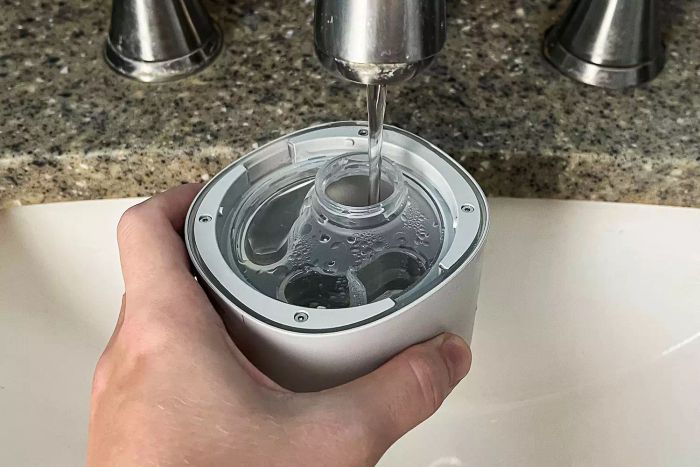 A person is filling the water canister of the Canopy Portable Humidifier