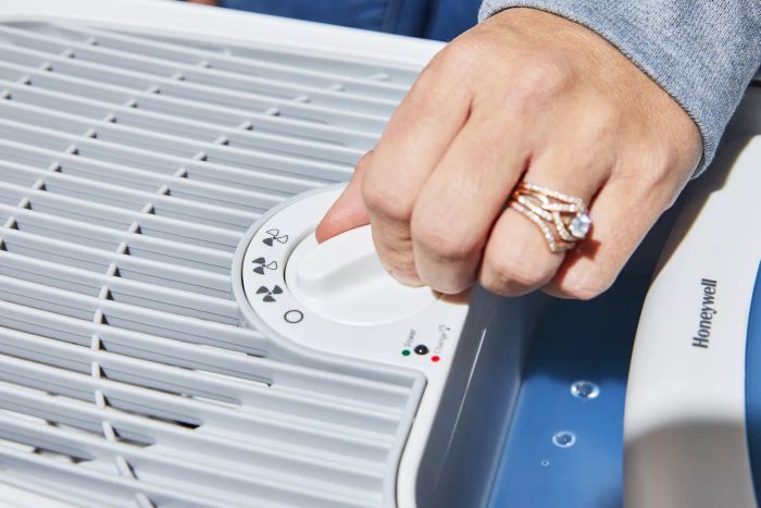 A hand is turning the dial on the Honeywell Cool Moisture Humidifier