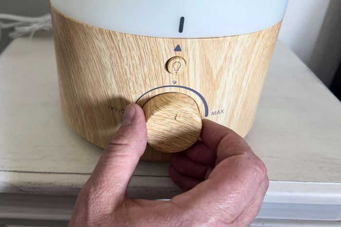 A person is adjusting the knob on the Levoit .8 Gallon Top-Filled Ultrasonic Cool Mist Humidifier