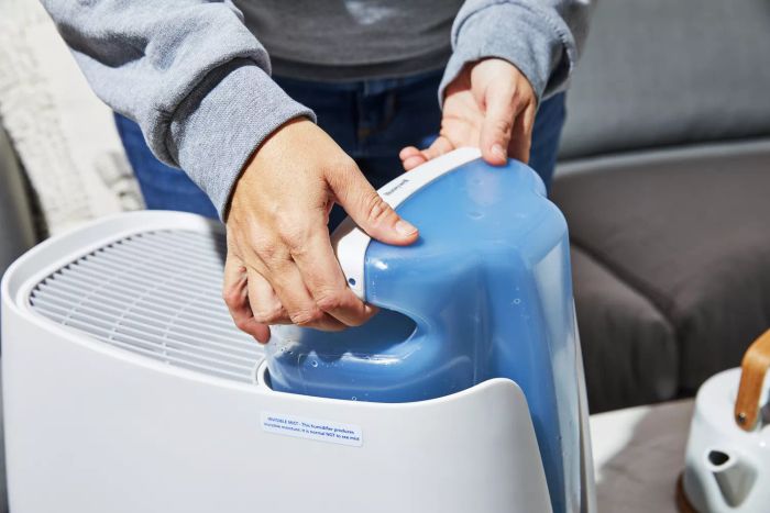 A person is removing the water tank from the Honeywell Cool Moisture Humidifier