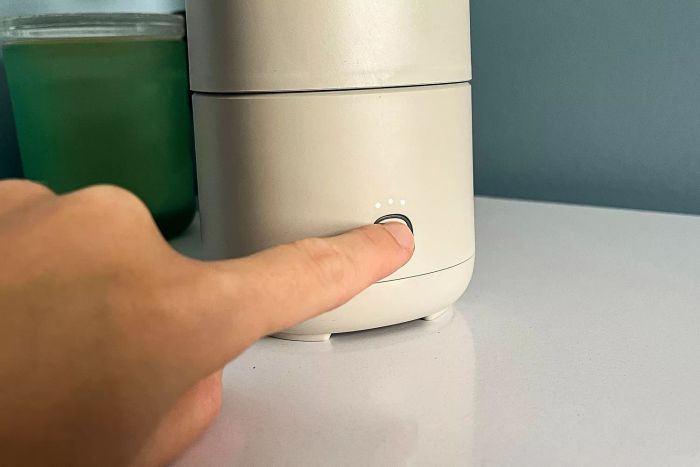 A person is pressing a button on the Canopy Portable Humidifier