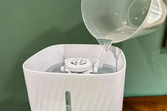A person is filling the Miko Myst Ultrasonic Humidifier with water