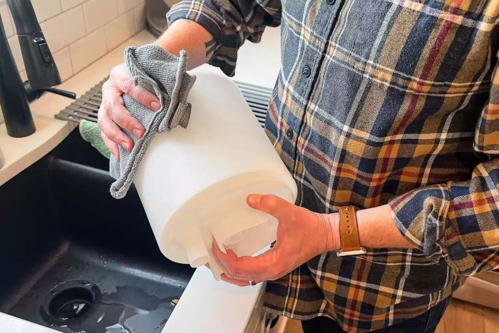 A person is wiping the canister of the Levoit .8 Gallon Top-Filled Ultrasonic Cool Mist Humidifier