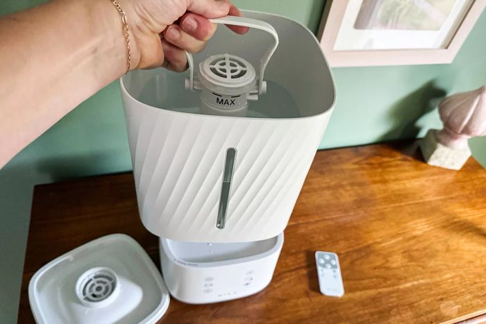 A person is seen placing the water-filled canister into the Miko Myst Ultrasonic Humidifier