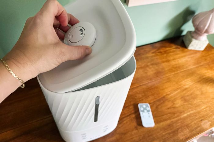 A person is removing the lid from the Miko Myst Ultrasonic Humidifier