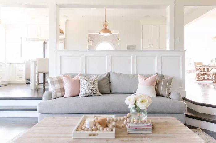 Living room featuring wainscoting on the wall, a gray sofa with pastel-colored pillows