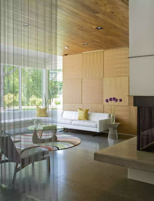 Contemporary living room featuring wooden 3D panels on the walls, a white sofa, and large windows