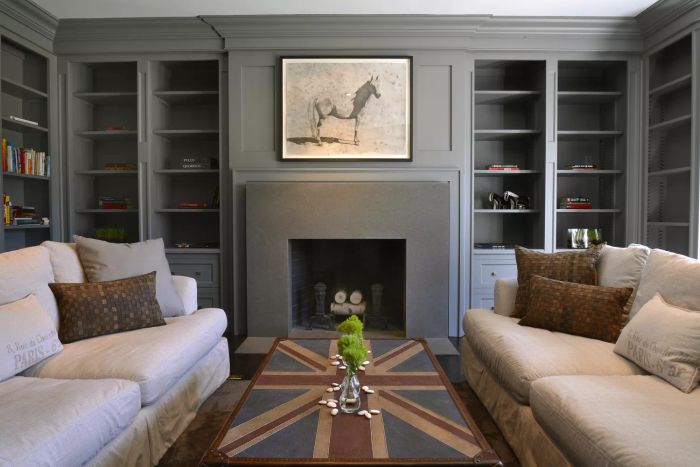 Bedroom featuring raised panels painted gray, a horse painting above the fireplace, and sofas