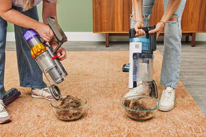 One person emptying the Dyson V15 Detect Cordless Vacuum Cleaner while another person empties a different vacuum cleaner