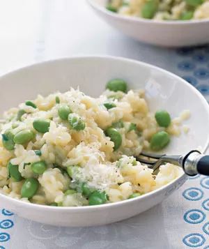 Risotto featuring edamame, lemon zest, and tarragon, served in two bowls with a fork on the side