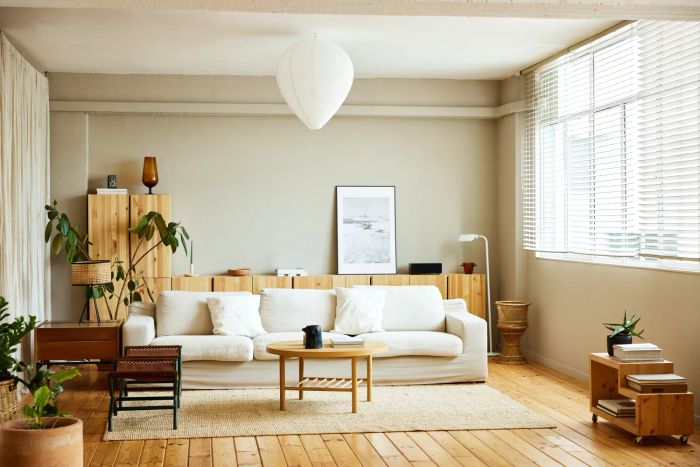 A sofa with a coffee table positioned by the window in the living room. A picture frame rests on a cabinet in a modern, bright apartment.