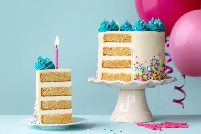 A birthday cake featuring layers of turquoise frosting, with a slice cut out and a pink birthday candle on top.