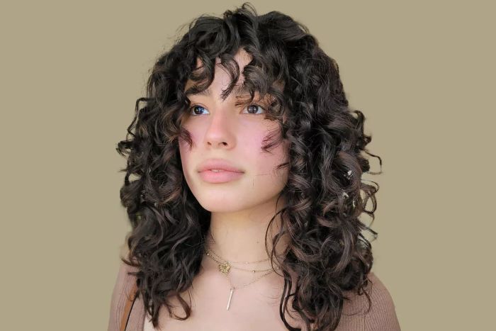 Close-up shot of a person sporting medium-length curly hair and bangs
