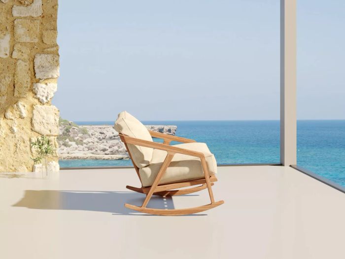 A solitary patio rocking chair featuring beige canvas cushions overlooking a water view