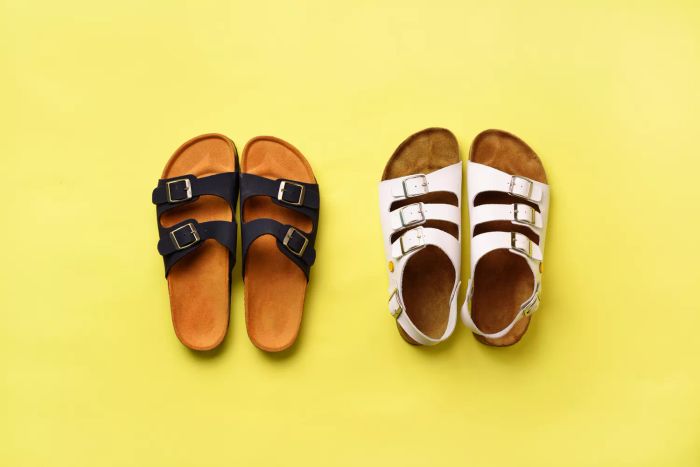 Summer women's footwear - Birkenstock sandals and slippers on a yellow background with copy space. Top view. Minimal flat lay. Selection concept.