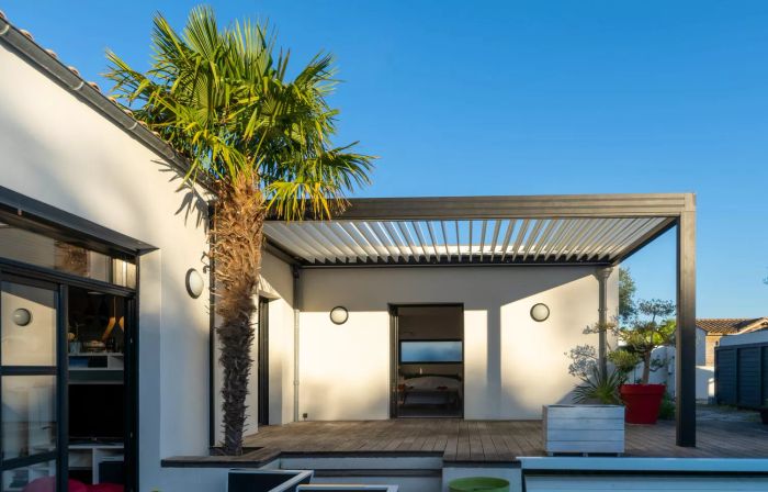 Stylish outdoor patio pergola, garden seating, chairs, and a metal grill set amidst lush landscaping
