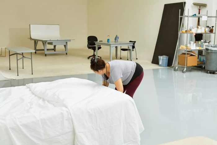 A woman arranging a bed with a white Boll & Branch Signature Hemmed Set.