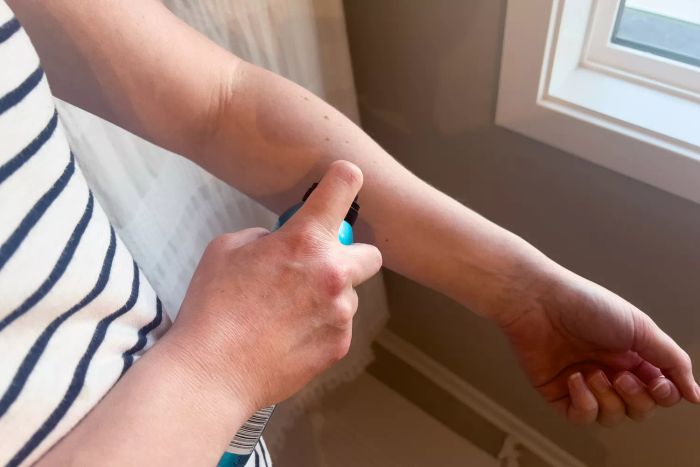 A person is using St. Tropez Self Tan Express Bronzing Mist on their arm.
