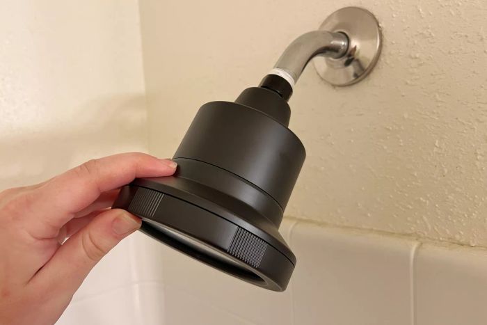 A hand holding the Act+Acre Filtered Showerhead