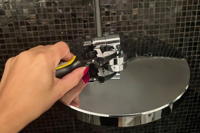 A hand using a tool to install the KOHLER 76465-G-BN Awaken Rain Shower Head